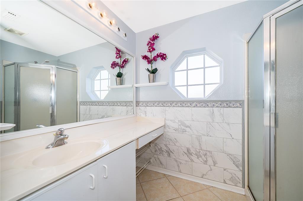 611 Baldwin Drive Kissimmee, FL 34758 - Photo 14 of 26 a bathroom with a granite countertop sink a mirror and a shower