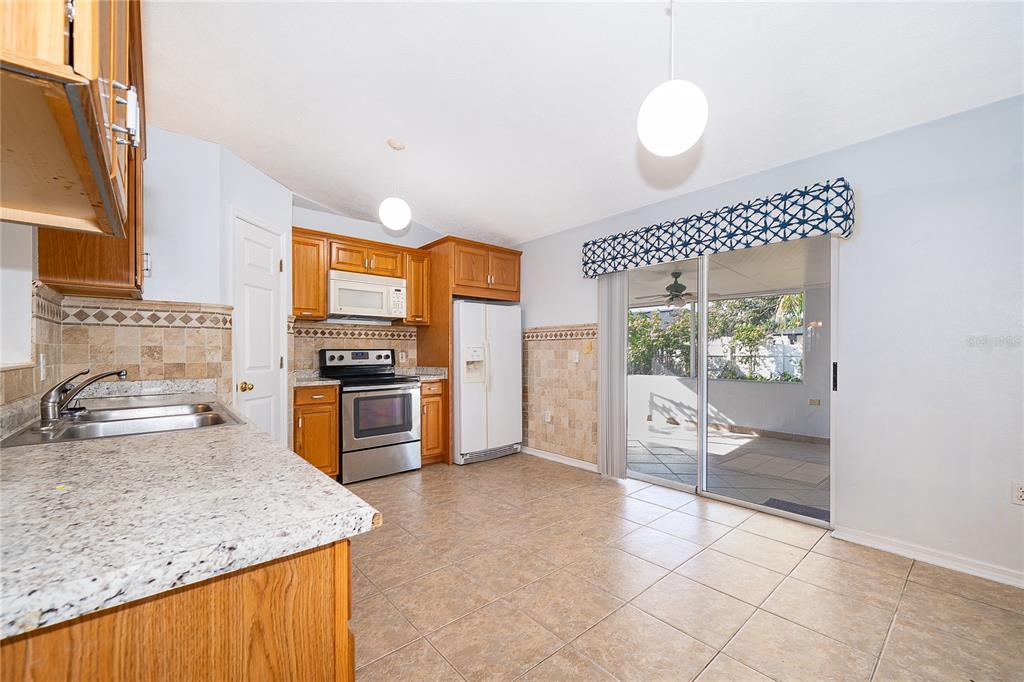 611 Baldwin Drive Kissimmee, FL 34758 - Photo 9 of 26 a kitchen with granite countertop a stove a sink and a refrigerator