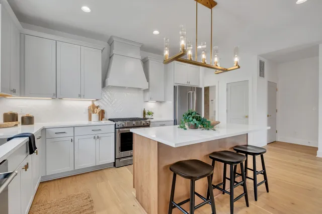 a kitchen with stainless steel appliances a dining table chairs sink and stove top oven