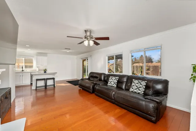 a living room with furniture and a dining table with wooden floor