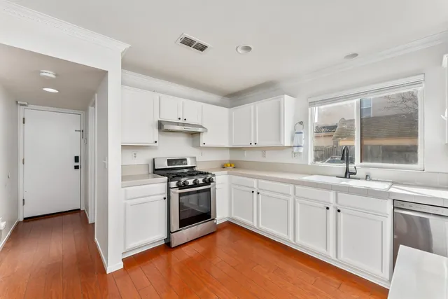 a kitchen with granite countertop white cabinets and stainless steel appliances