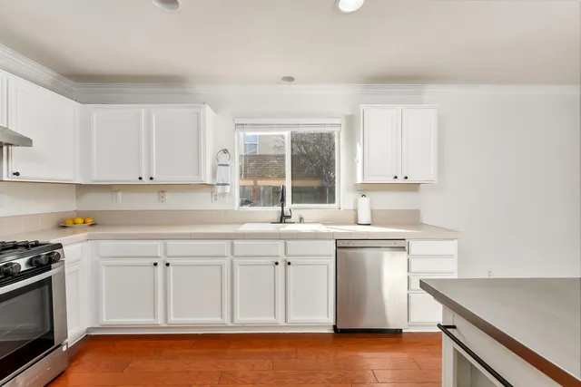 a kitchen with stainless steel appliances granite countertop a sink and cabinets with wooden floor