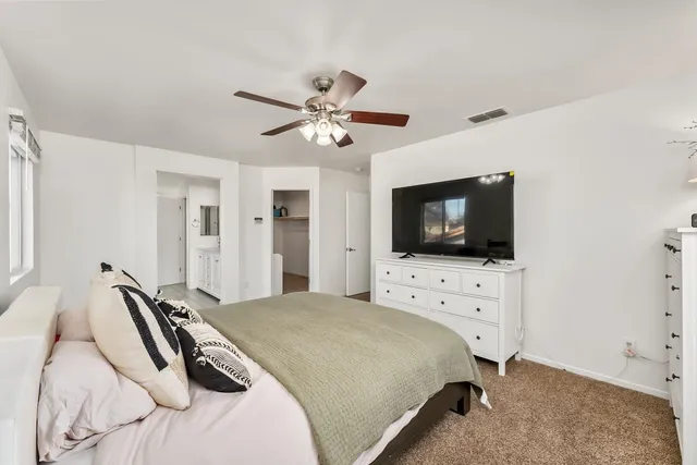 a bedroom with a bed a flat screen tv and a chandelier