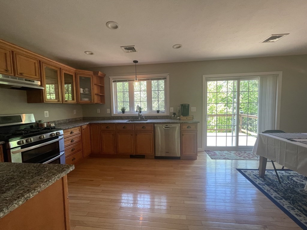 32 Jericho Road Rindge, NH 03461 - Photo 9 of 37 a large kitchen with stainless steel appliances granite countertop a stove a sink wooden cabinets and a large window