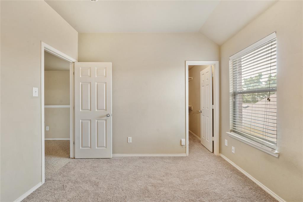 2003 Diamondback Forney, TX 75126 - Photo 21 of 30 Unfurnished bedroom featuring light carpet, vaulted ceiling, and a walk in closet
