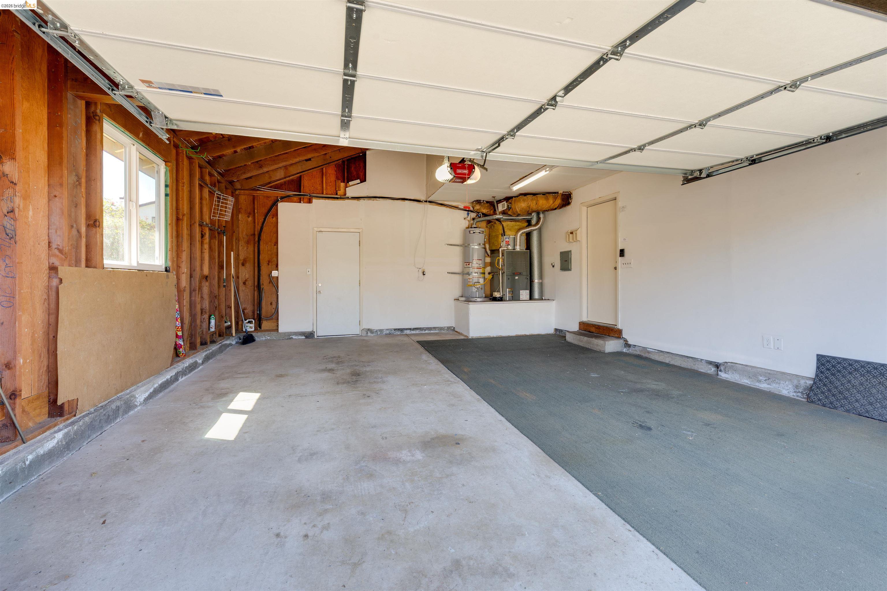 2142 Redwood Road Hercules, CA 94547 - Photo 30 of 37 Garage featuring strapped water heater, a garage door opener, and electric panel