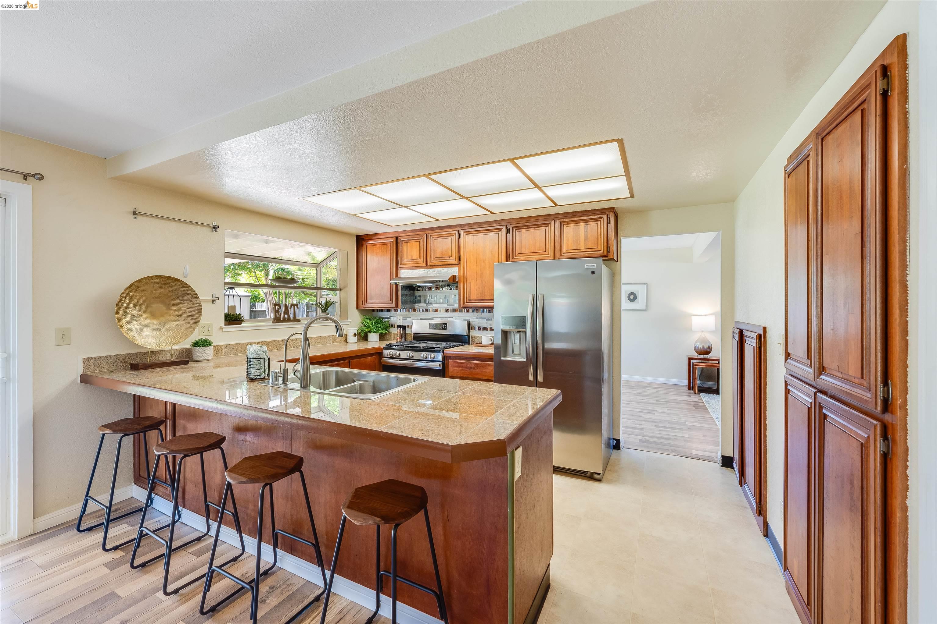 2142 Redwood Road Hercules, CA 94547 - Photo 10 of 37 Kitchen with wood finish cabinetry, a breakfast bar area, stainless steel appliances, a peninsula, and tile countertops
