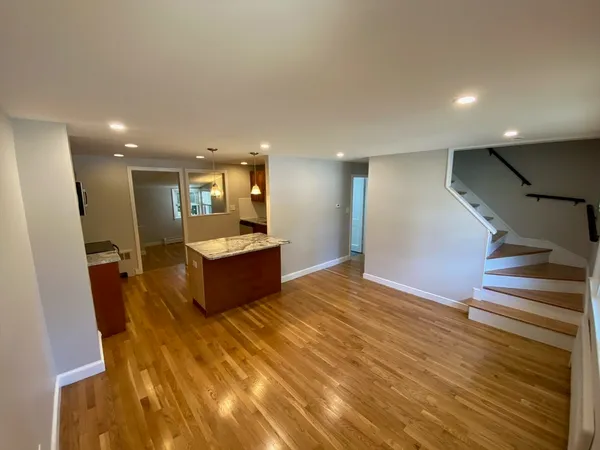 a large room with kitchen island a sink wooden floor and a living room view