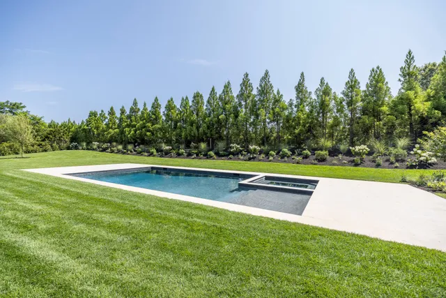 a view of a brick house next to a yard with large trees