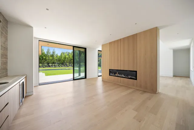 a view of an empty room with a window and kitchen view
