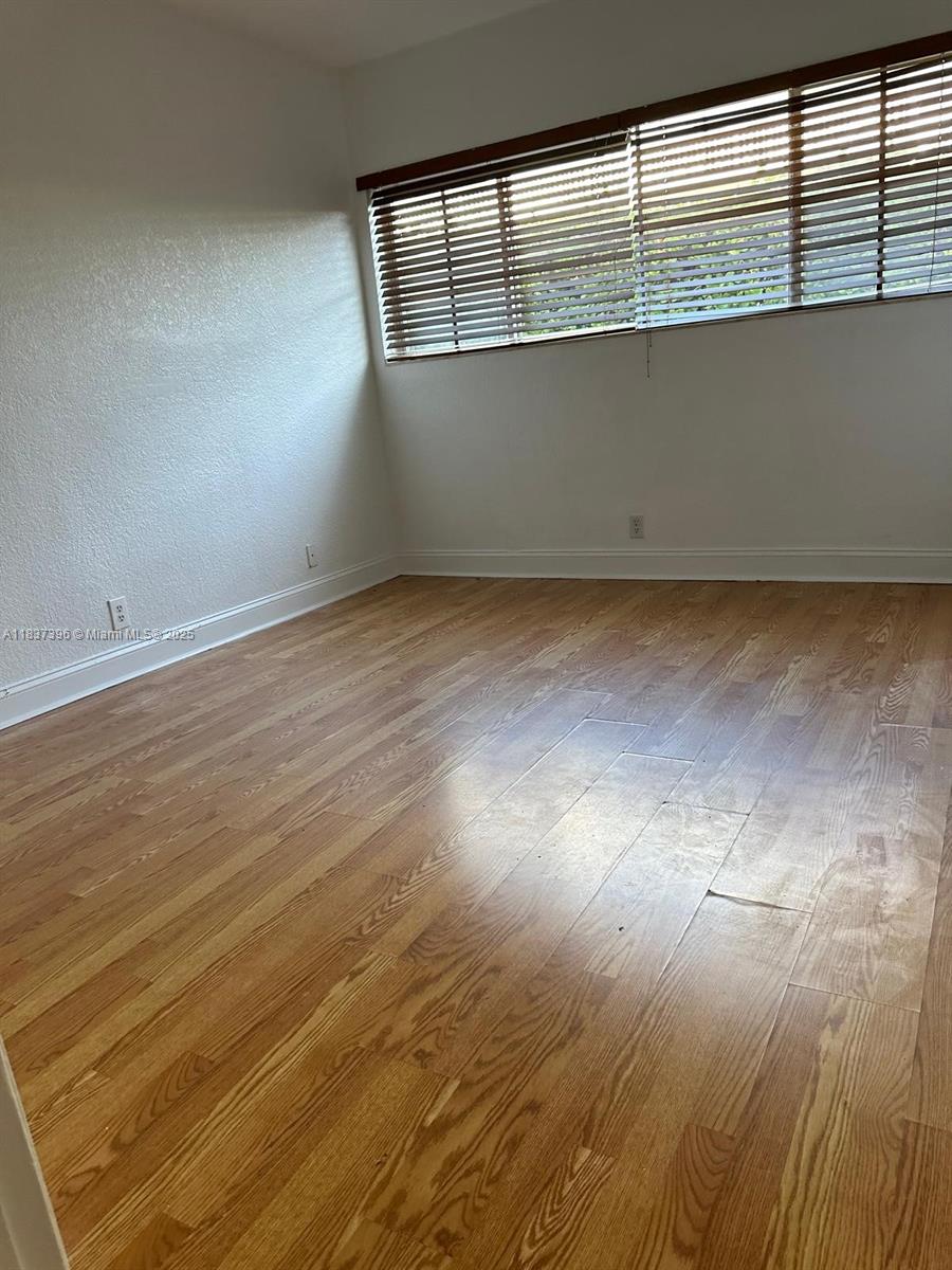 1065 97th Street, Unit 1A Bay Harbor Islands, FL 33154 - Photo 11 of 14 an empty room with wooden floor and windows