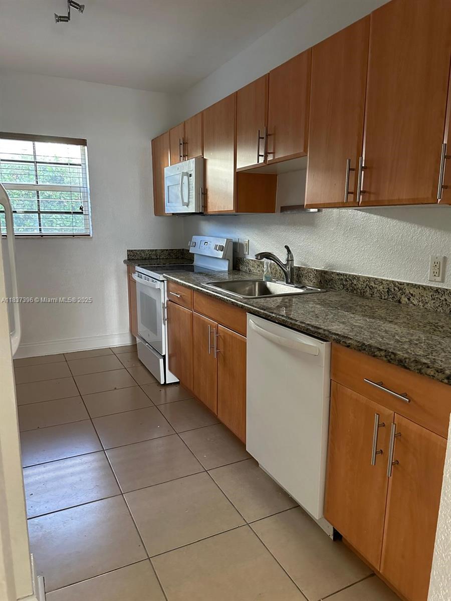 1065 97th Street, Unit 1A Bay Harbor Islands, FL 33154 - Photo 5 of 14 a kitchen with stainless steel appliances granite countertop a sink and cabinets