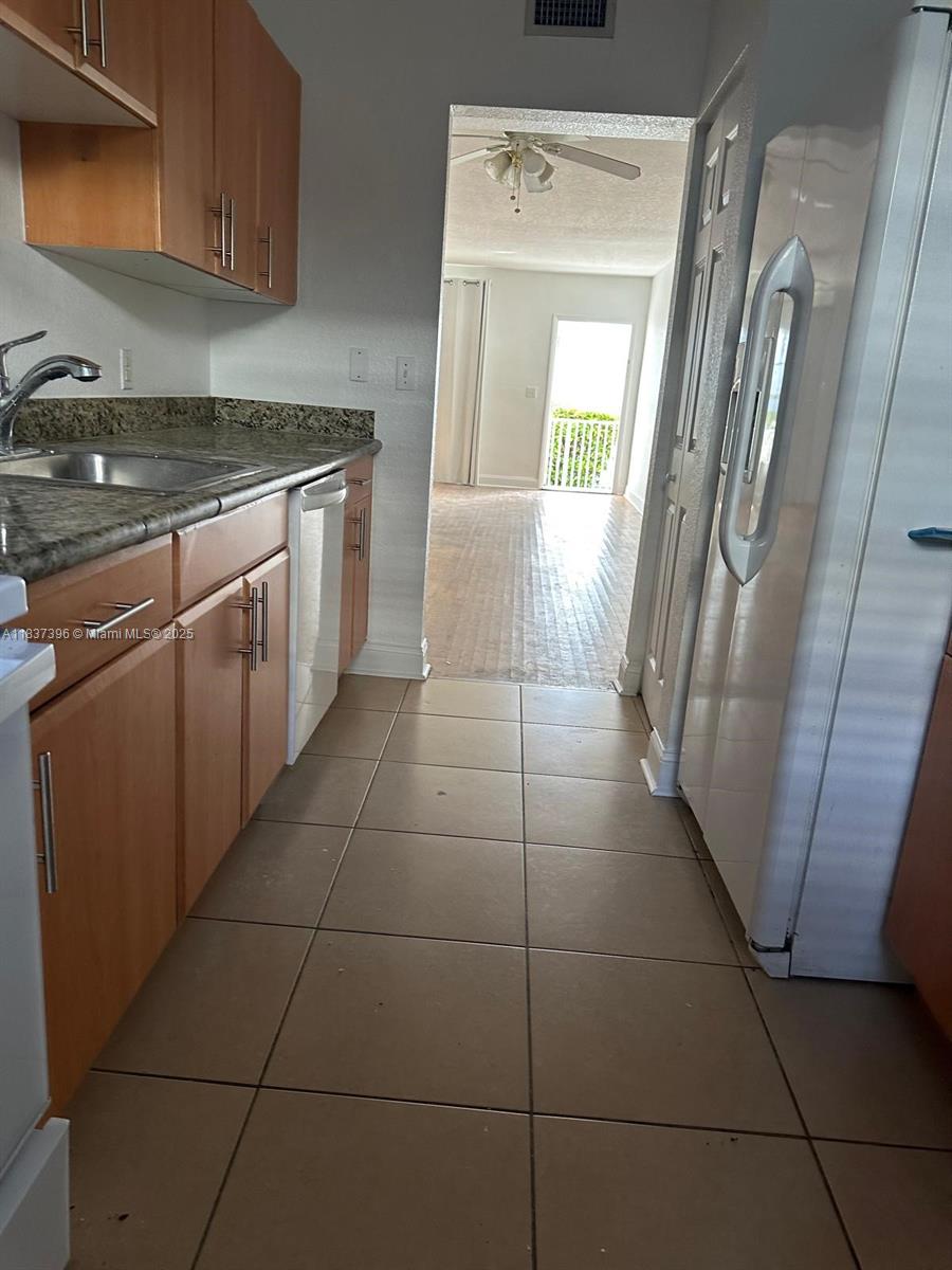 1065 97th Street, Unit 1A Bay Harbor Islands, FL 33154 - Photo 6 of 14 a kitchen with granite countertop a stove a sink and a refrigerator