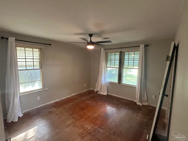 an empty room with wooden floor and windows