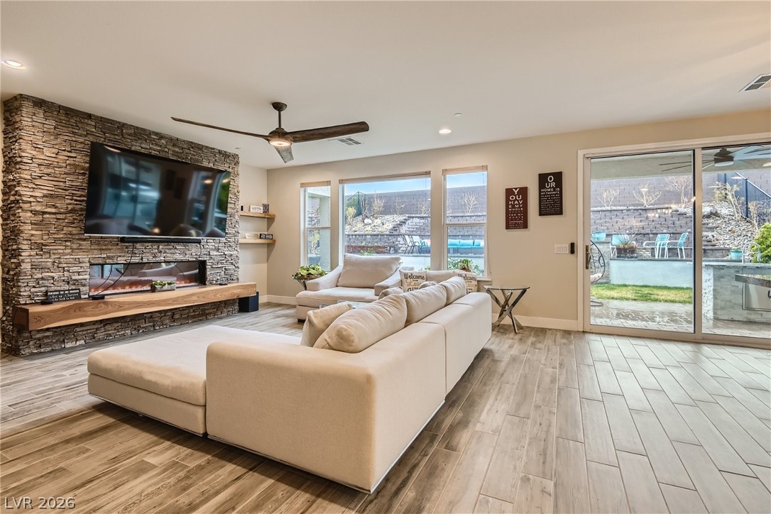 4631 Amazing View Street Las Vegas, NV 89129 - Photo 5 of 33 An inviting open-concept living space features a stone fireplace, sleek wooden flooring, and ample natural light.