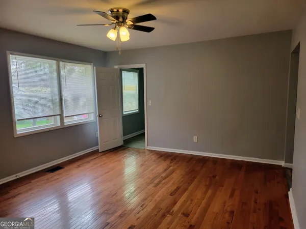 a view of an empty room with window and wooden floor