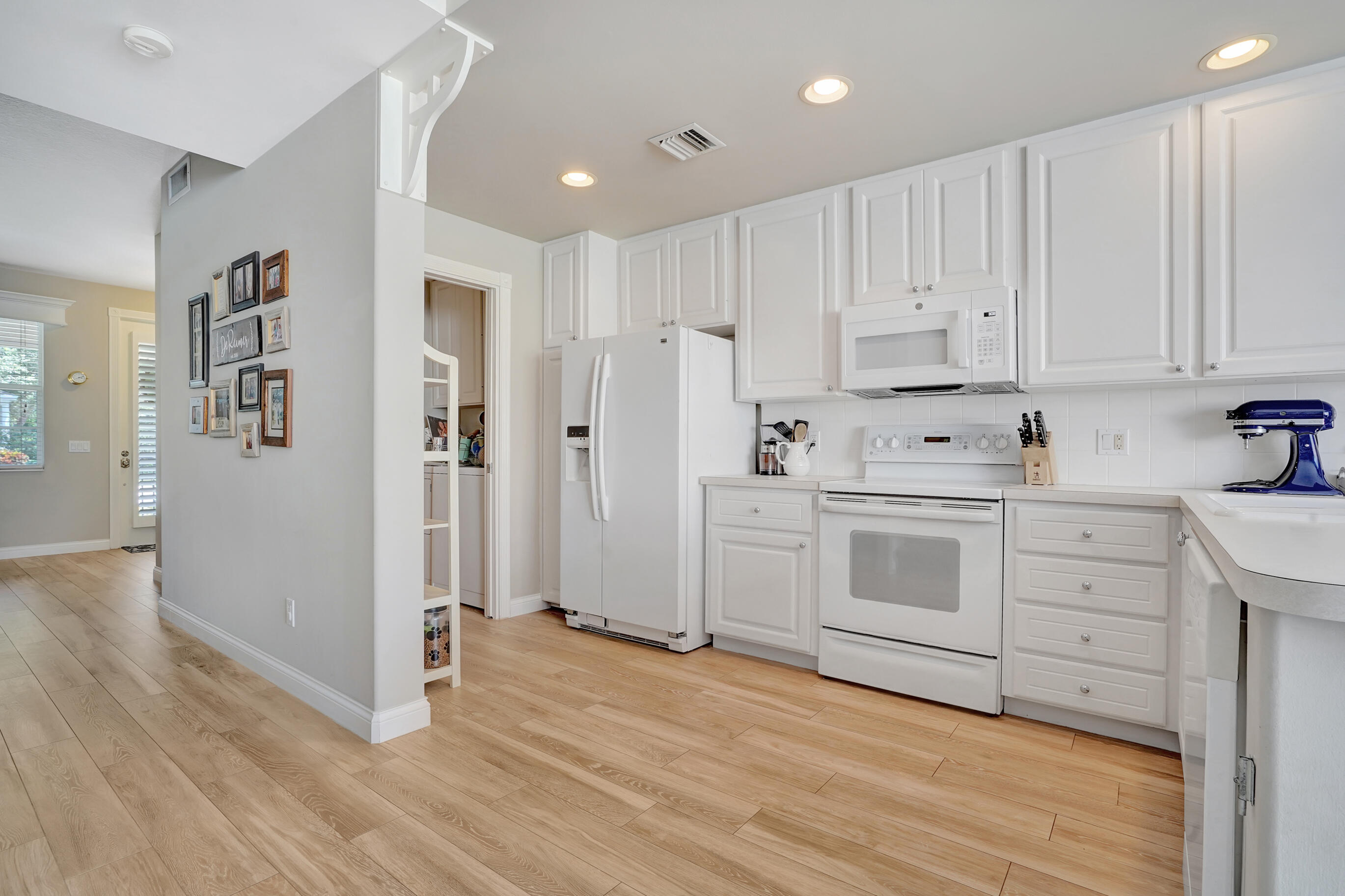 1687 Frederick Small Road Jupiter, FL 33458 - Photo 6 of 27 a kitchen with white cabinets and white appliances