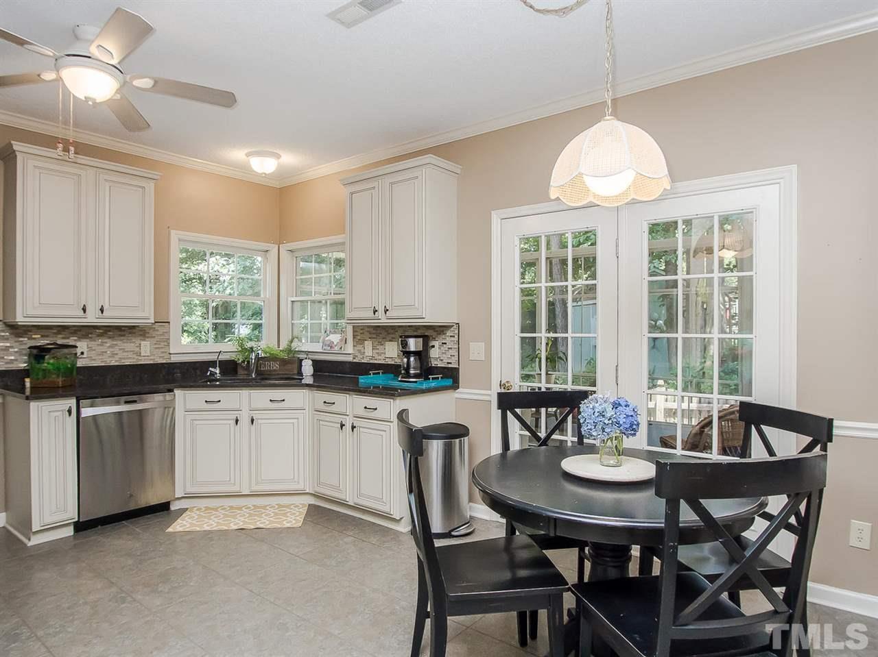 3400 Ribcowski Court Raleigh, NC 27616 - Photo 10 of 25 a kitchen with granite countertop a dining table chairs and white cabinets