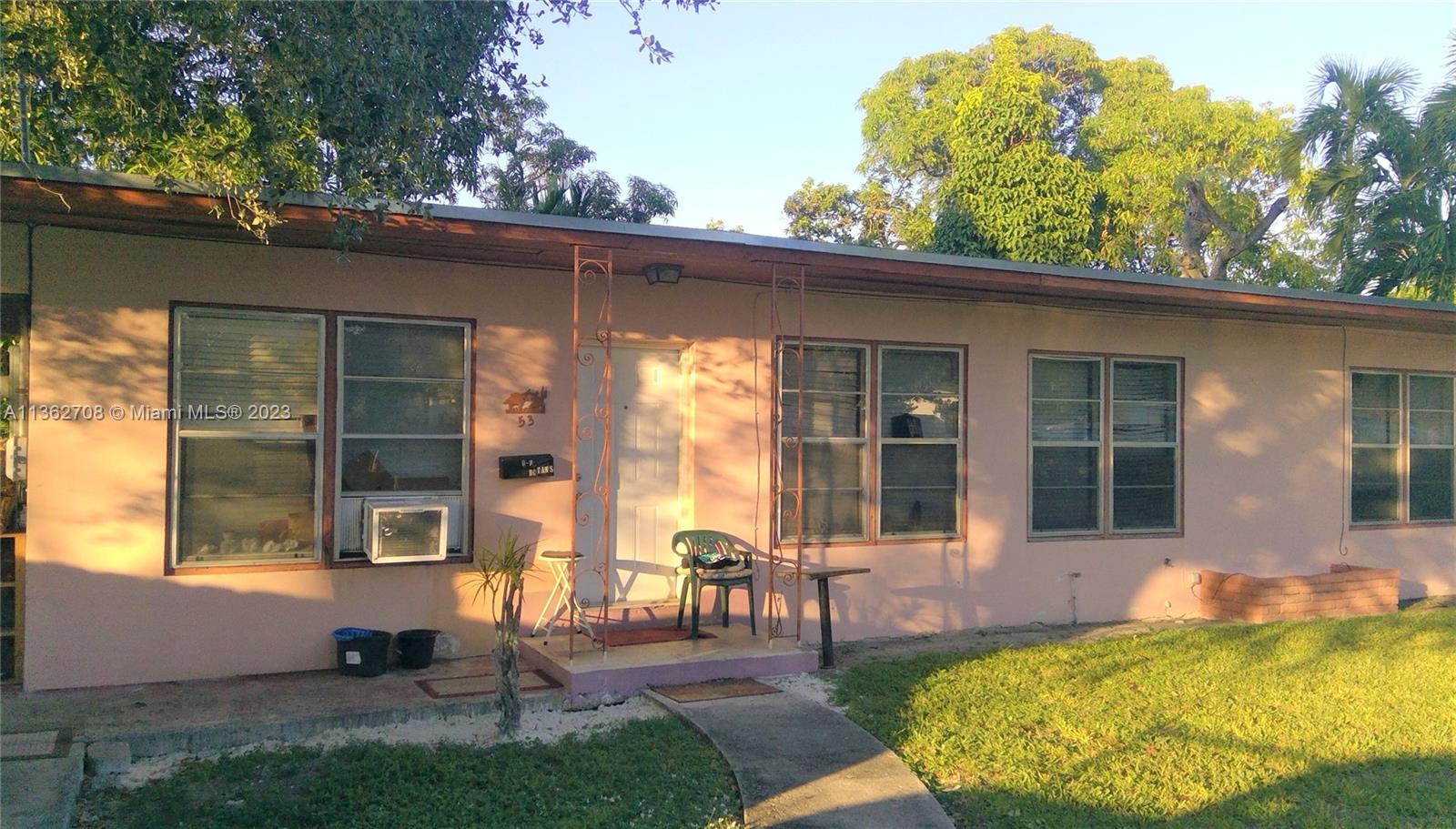 a view of a house with pool chairs and a yard