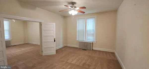 an empty room with closet and a ceiling fan