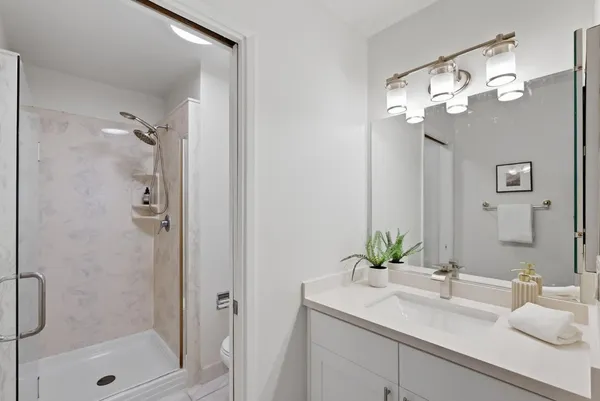 a bathroom with a sink vanity granite shower and a mirror