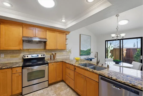 a kitchen with stainless steel appliances granite countertop a stove a sink and a microwave