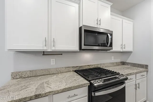 a kitchen with granite countertop white cabinets and stainless steel appliances