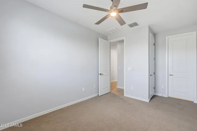 an empty room with a fan & a window