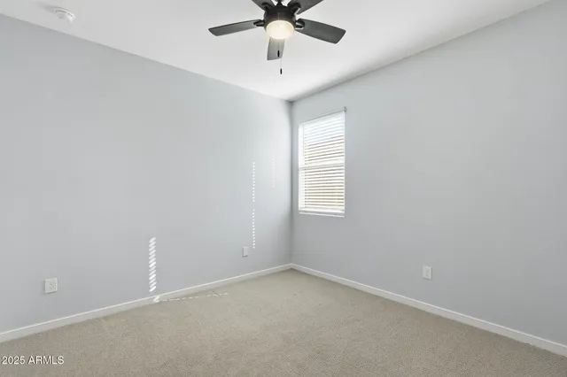 an empty room with a window and a ceiling fan