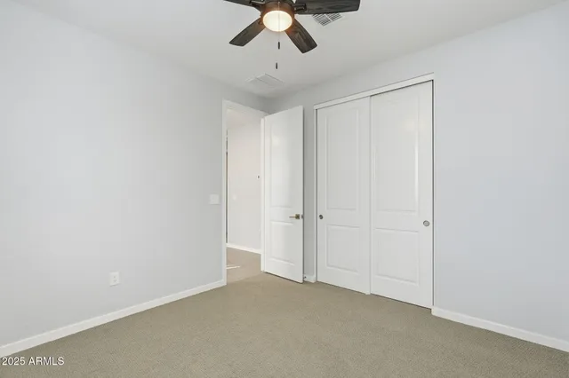 a view of an empty room and chandelier fan