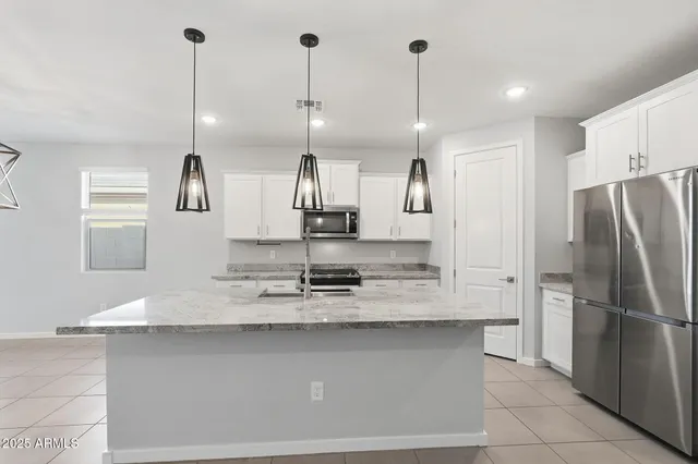 a kitchen with stainless steel appliances granite countertop a sink a refrigerator a counter and cabinets