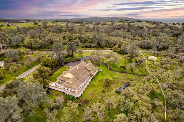 a view of a house with a big yard and large trees