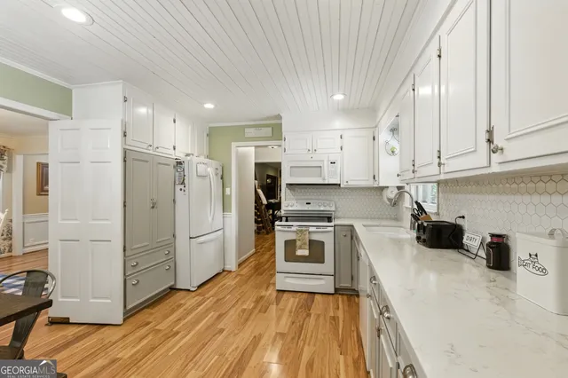 a kitchen with a refrigerator a stove top oven and white cabinets