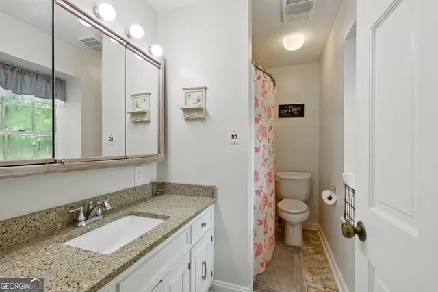 a bathroom with a granite countertop sink toilet and shower