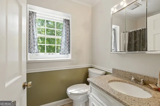 a bathroom with a granite countertop toilet a sink and a mirror