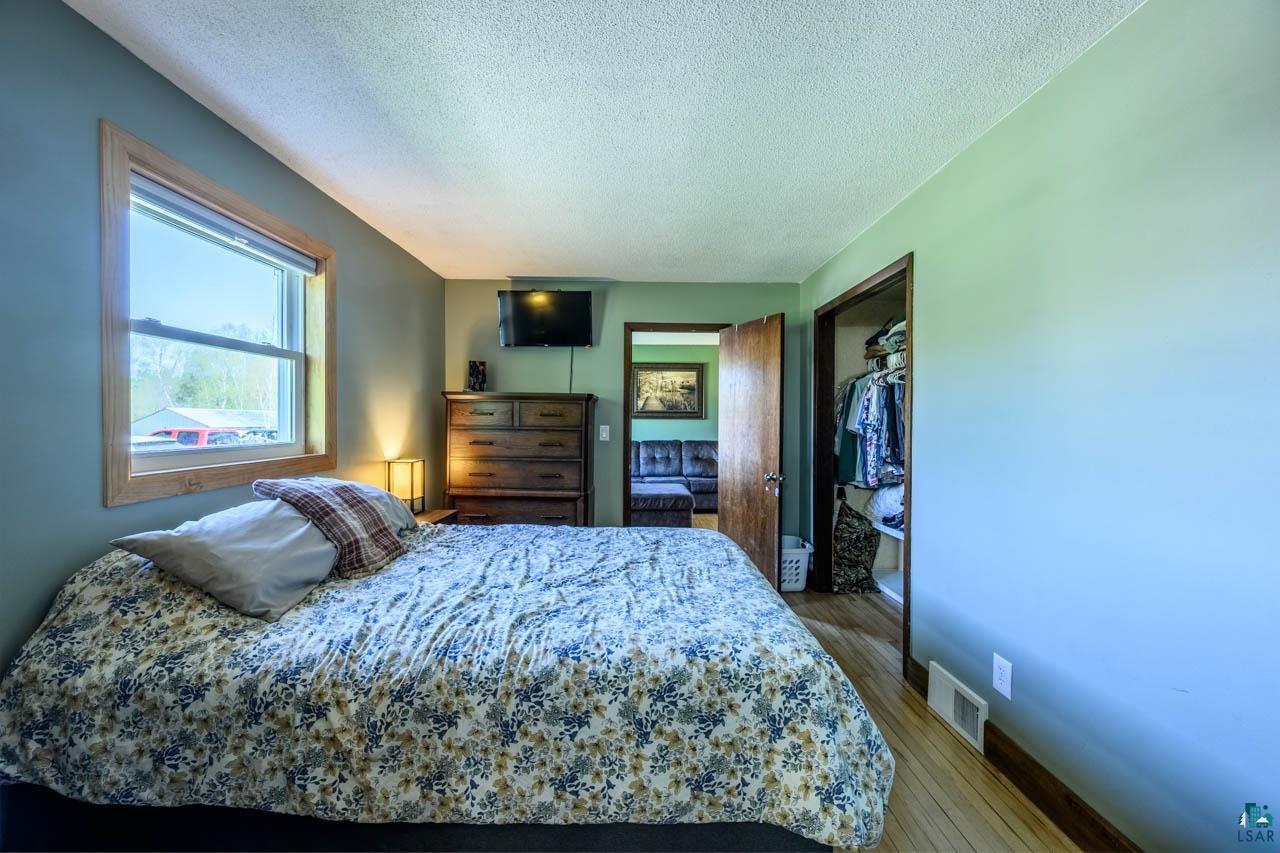 2581 O'Rourke Road Hibbing, MN 55746 - Photo 15 of 61 Bright interior room featuring a window with natural wood trim, light wood-finish flooring, and a built-in closet with shelving