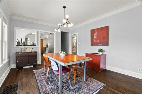 a dining room with wooden floor a chandelier a wooden table and chairs