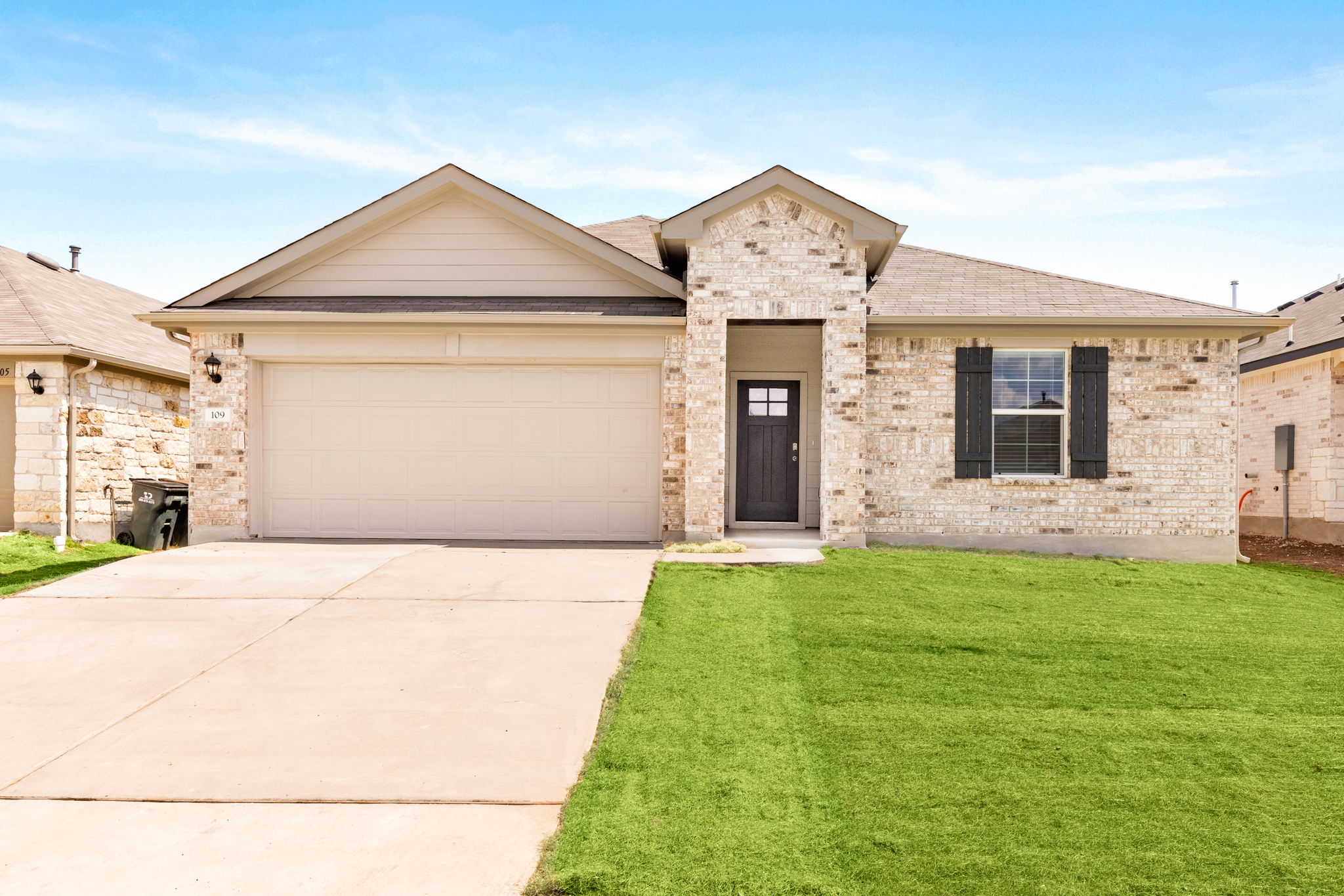 109 Docile Loop San Marcos, TX 78666 - Photo 1 of 1 View of front of home featuring a front yard, driveway, a garage, and brick siding