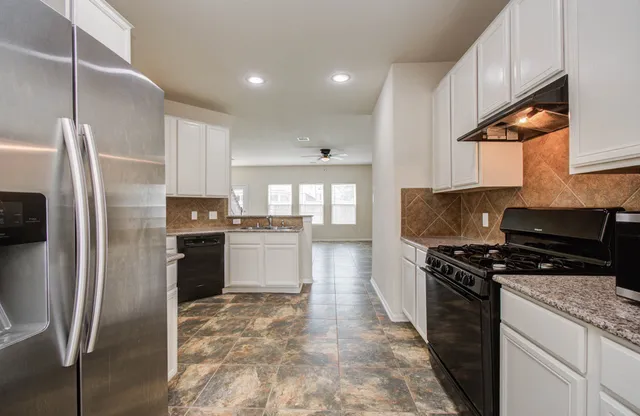 a kitchen with stainless steel appliances granite countertop a stove a refrigerator and a sink