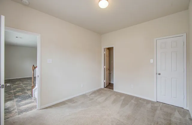 a view of an empty room with window and chandelier fan
