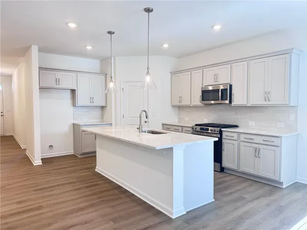 a kitchen with stainless steel appliances white cabinets a sink a stove a refrigerator and a microwave