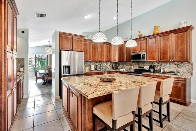 a kitchen with stainless steel appliances granite countertop a stove a refrigerator a kitchen island a sink a dining table and chairs