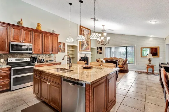 a kitchen with stainless steel appliances granite countertop a stove a sink dishwasher and a refrigerator with wooden floor