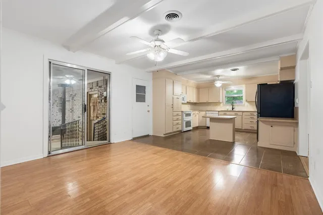 a view of an empty room with kitchen and a window