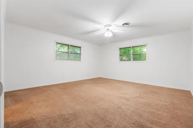 an empty room with windows and fan
