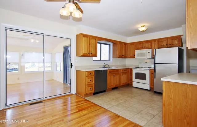 a kitchen with stainless steel appliances granite countertop a refrigerator a sink dishwasher a stove with wooden cabinets and floors