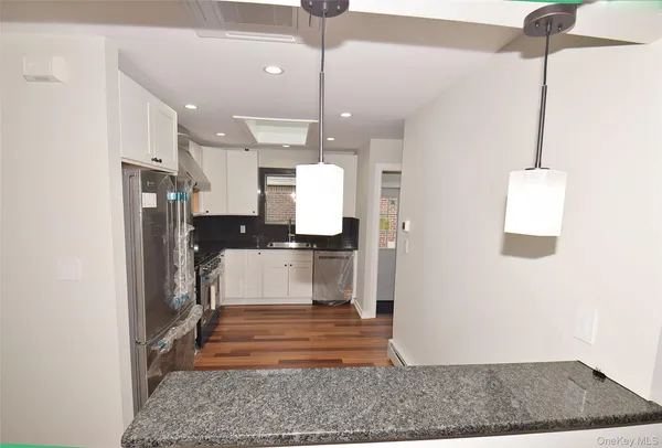 a view of a kitchen with white cabinets and stainless steel appliances