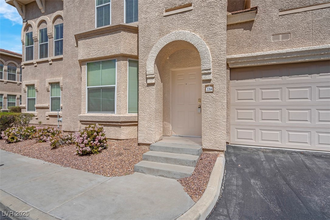 10550 West Alexander Road, Unit 2064 Las Vegas, NV 89129 - Photo 3 of 51 Doorway to property with a garage and stucco siding