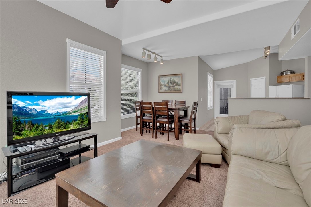 10550 West Alexander Road, Unit 2064 Las Vegas, NV 89129 - Photo 8 of 51 Carpeted living room featuring baseboards, rail lighting, a ceiling fan, visible vents, and lofted ceiling