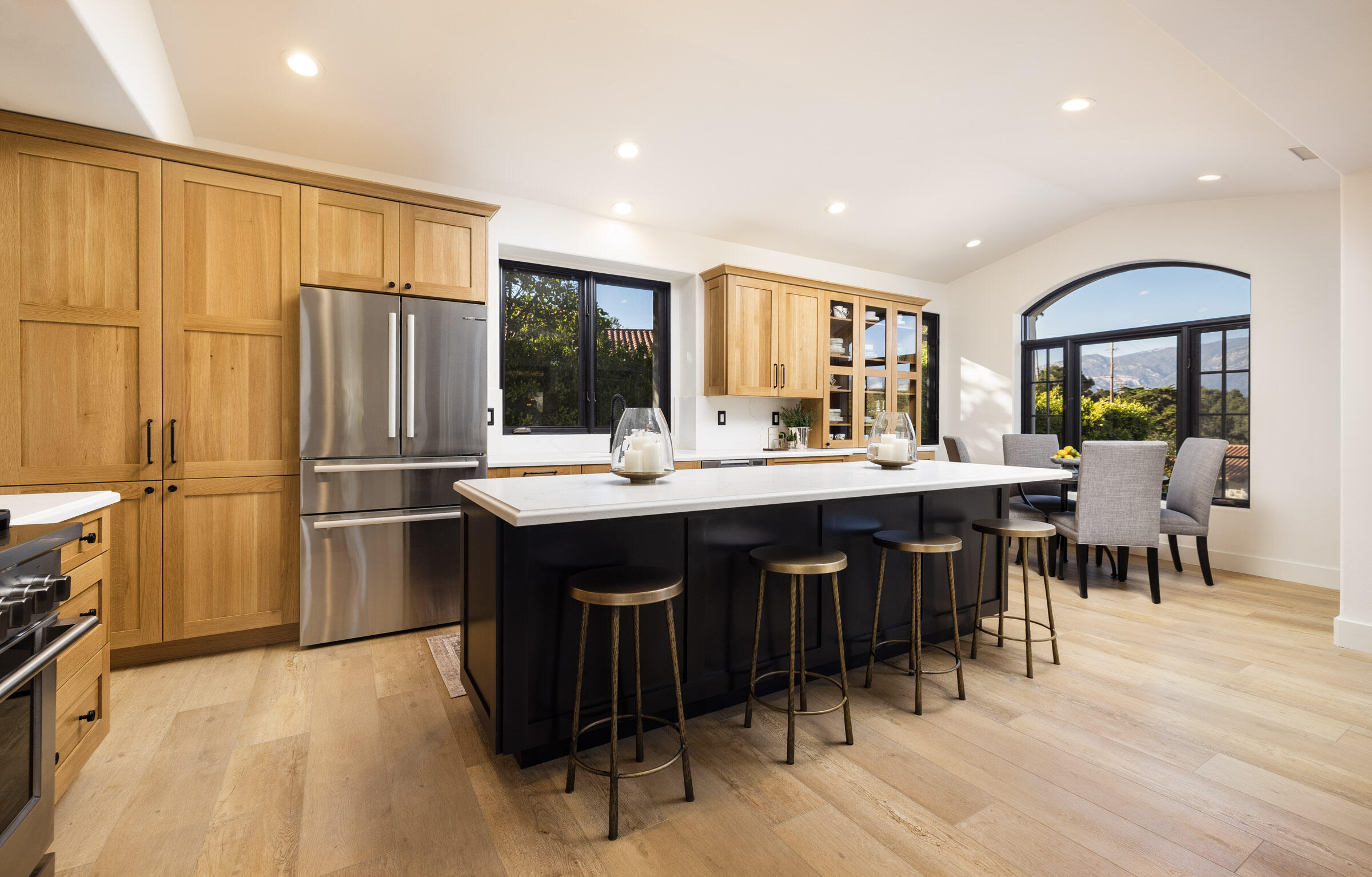 1215 Miracanon Lane Santa Barbara, CA 93109 - Photo 7 of 40 a kitchen with stainless steel appliances granite countertop a refrigerator a stove a sink a dining table and chairs with wooden floor